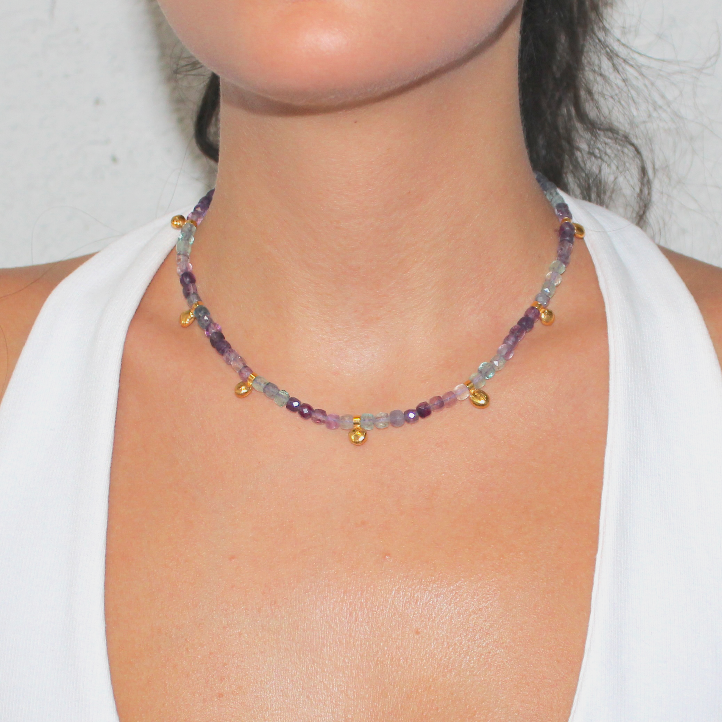 Necklace with multicolored fluorite beads and gold charm worn by a person