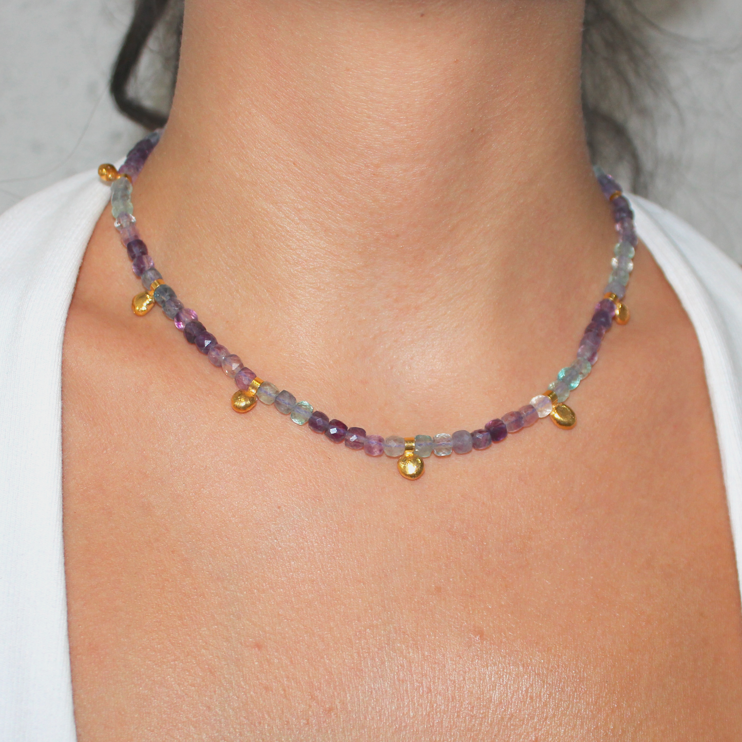 Necklace with multicolored fluorite beads and gold charm worn by a person