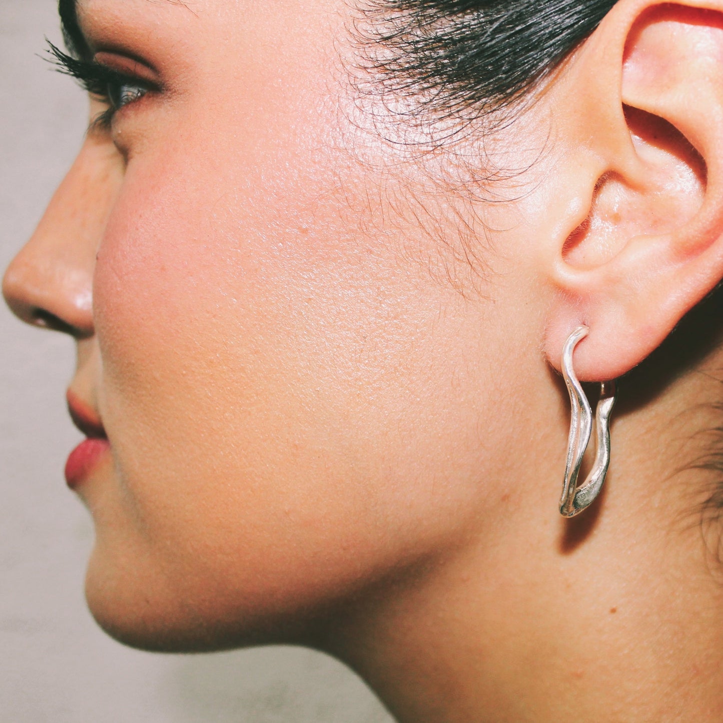 Close-up of a person wearing a silver hoop earring.