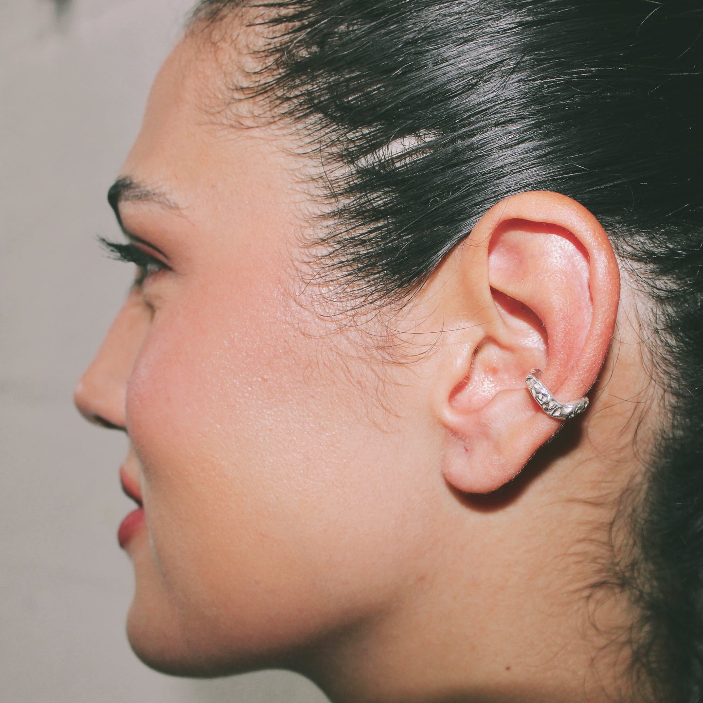 Close-up of a person's ear with an ear cuff against a neutral background jewellery handmade lisbon