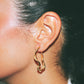 Close-up of a person wearing a gold hoop earring with a neutral background handmade jewelry lisbon