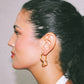 Close-up of a person wearing a gold hoop earring with a neutral background handmade jewelry lisbon