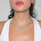 Aquamarine Turquoise beaded necklace with gold starfish marine charms worn by a person.