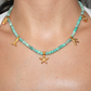 Necklace with aquamarine turquoise beads and gold starfish marine pendants charms on a person's neck.