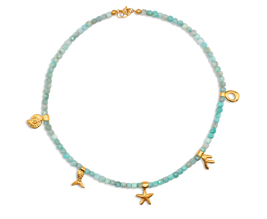 Necklace with turquoise aquamarine beads and gold charms on a white background